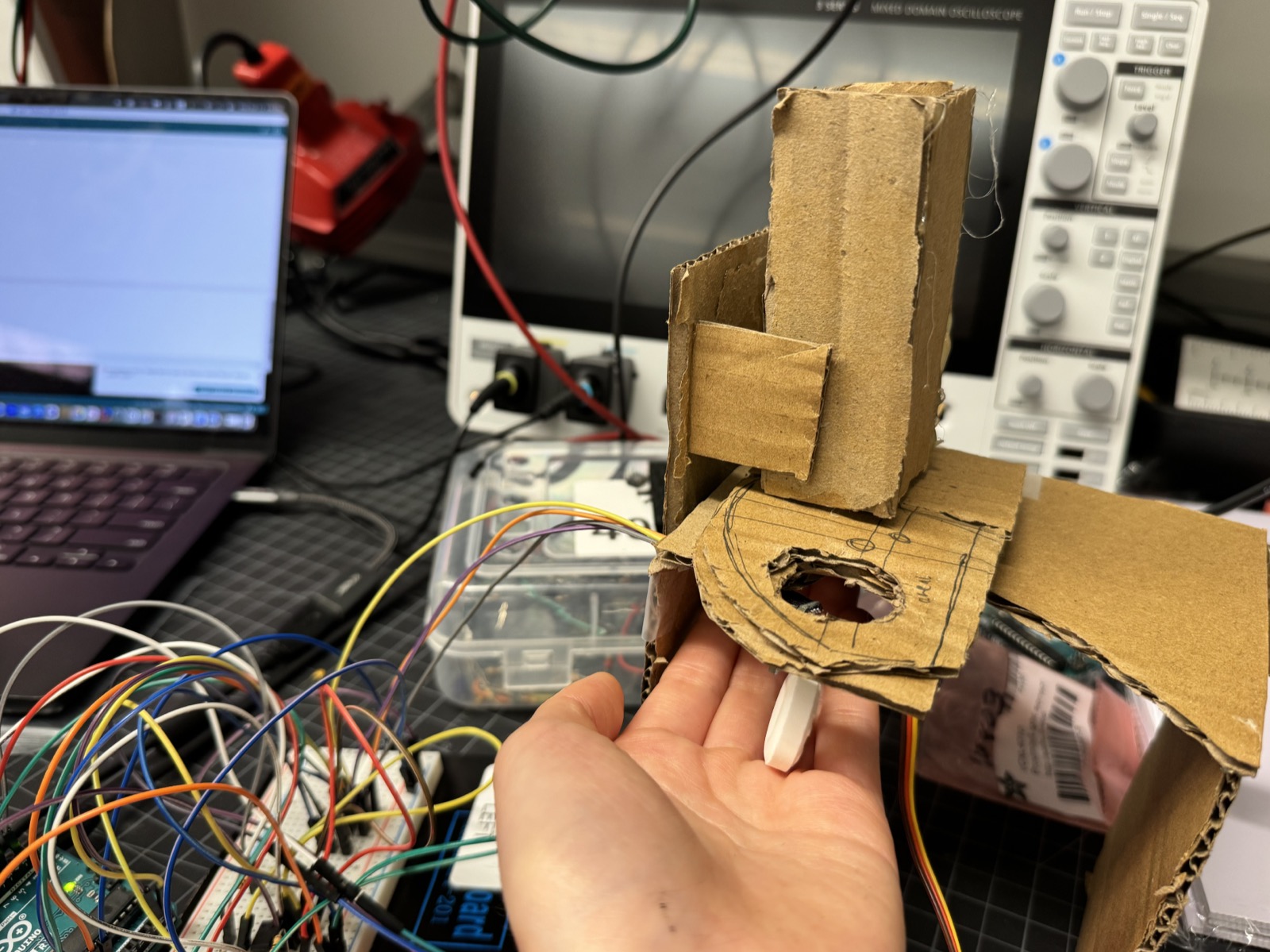 The servo mechanism at roughly 90 degrees of rotation, dispensing a mint through the cardboard chassis.